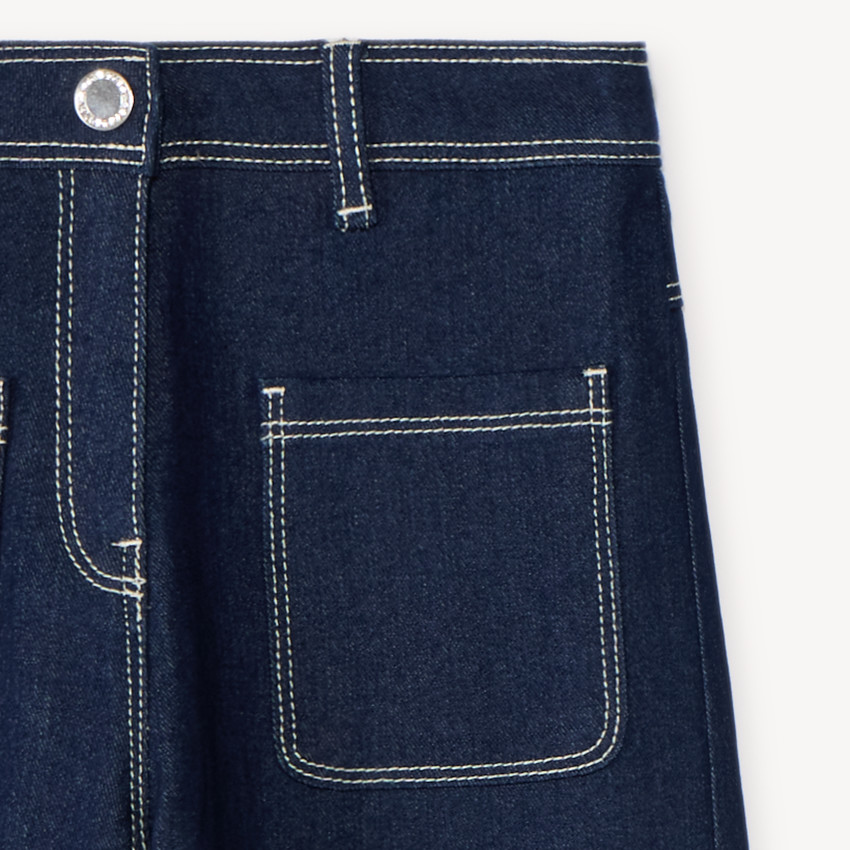 Pantalón de niña de corte amplio, liso y con bolsillos de parche. 