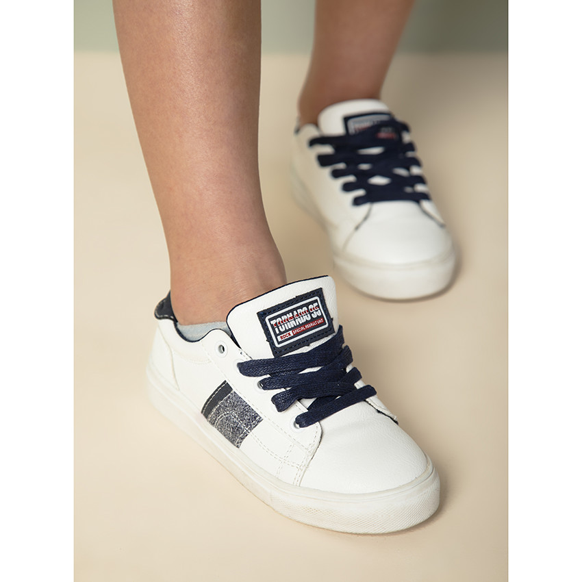 Zapatillas bajas blancas con bandas laterales para niño. 