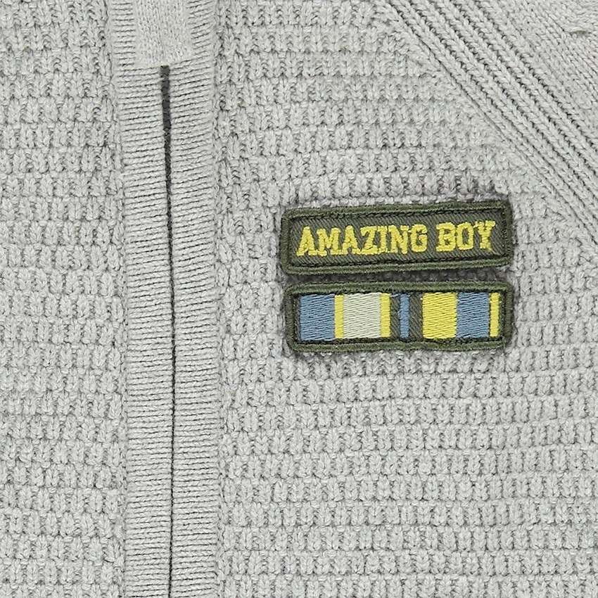 Chaqueta de punto con cremallera y parche de insignia en el pecho. 